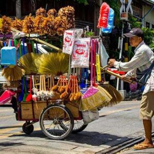 A man selling brooms with a push car on the streets of Bangkok